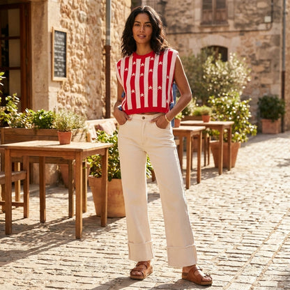 Woman in striped top and white pants standing on a cobblestone street.