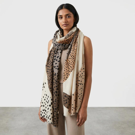 Woman wearing a polka dot scarf and neutral-toned outfit.