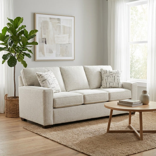 Modern living room with a beige sofa, round table, plant, and abstract art.