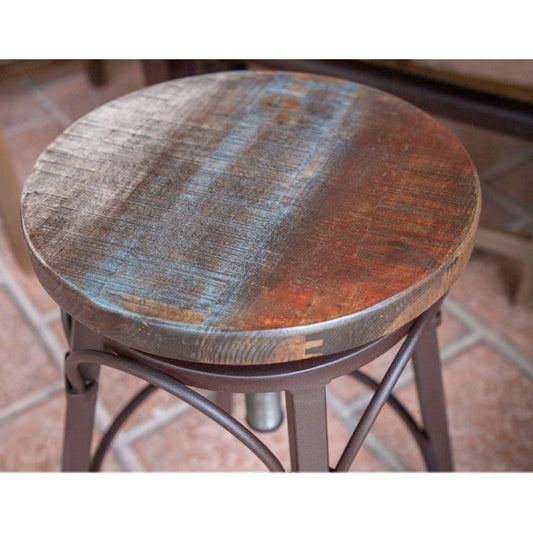 Rustic wooden stool with iron legs on a tiled floor.