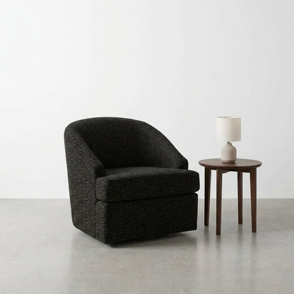 Cozy black chair and lamp on a wooden table in a minimalist room.