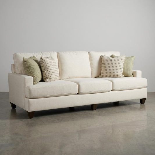 Beige sofa with patterned throw pillows on a concrete floor.