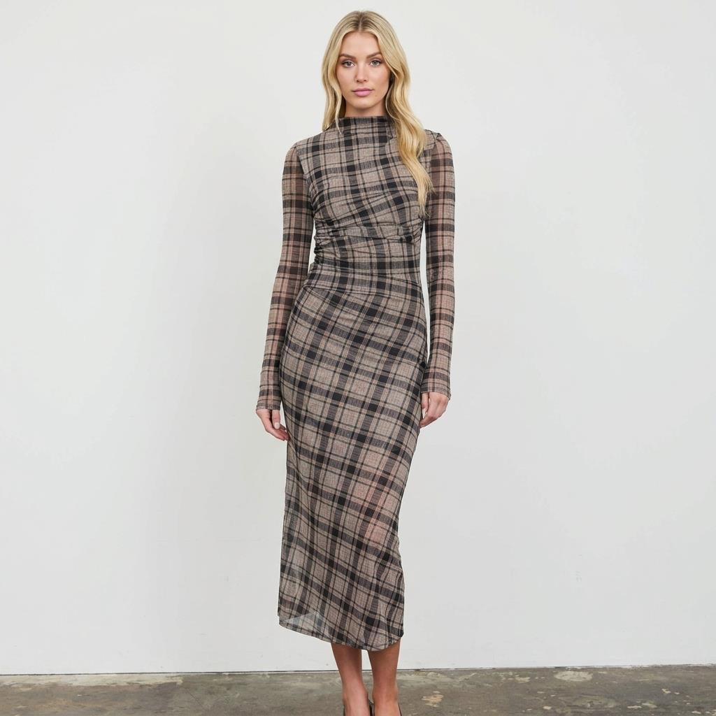Woman in a long plaid dress poses against a white background.