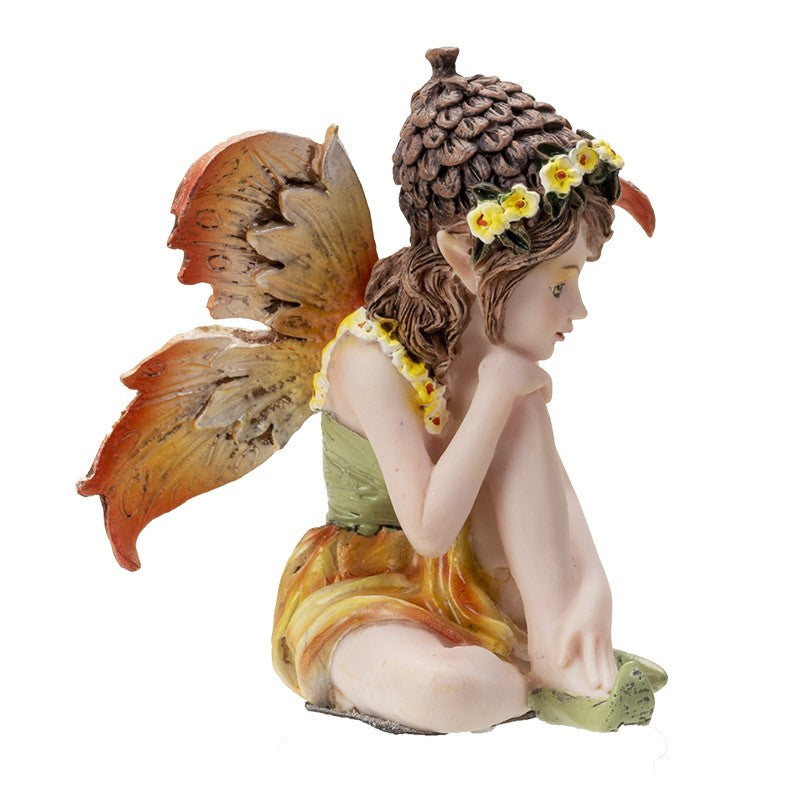 Fairy figurine with acorn cap and colorful wings, sitting and pondering.