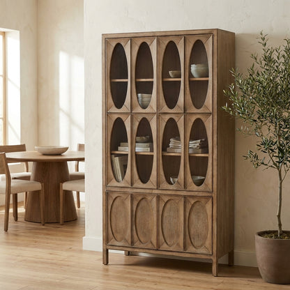 Wooden cabinet with oval glass panels beside round dining table.
