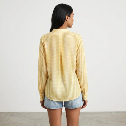 Woman in yellow striped shirt and denim shorts, facing away.