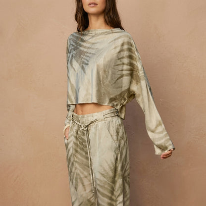 Woman in tie-dye loungewear against a beige wall.