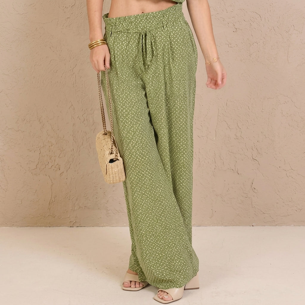 Woman wearing green pants, carrying a small woven bag.