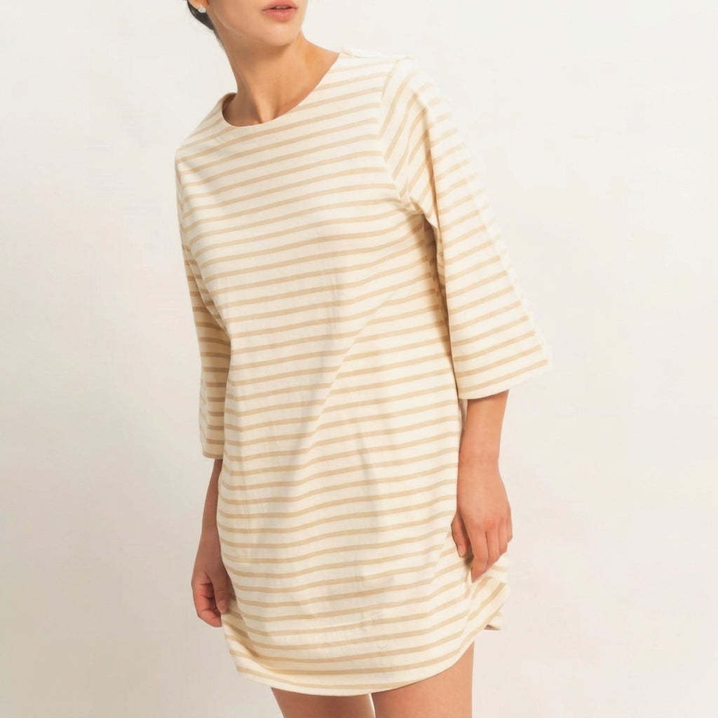 Person in a striped beige dress, looking sideways.