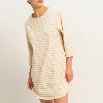 Person in a striped beige dress, looking sideways.