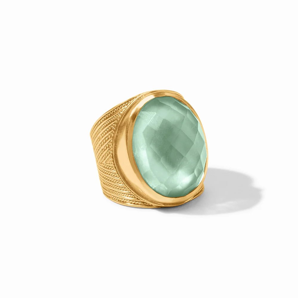Gold ring with an ornate band and a large faceted pale aqua gemstone.