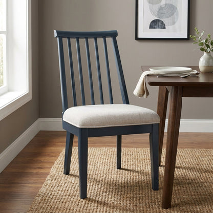 Dark blue chair beside table on woven rug in a minimalist room.