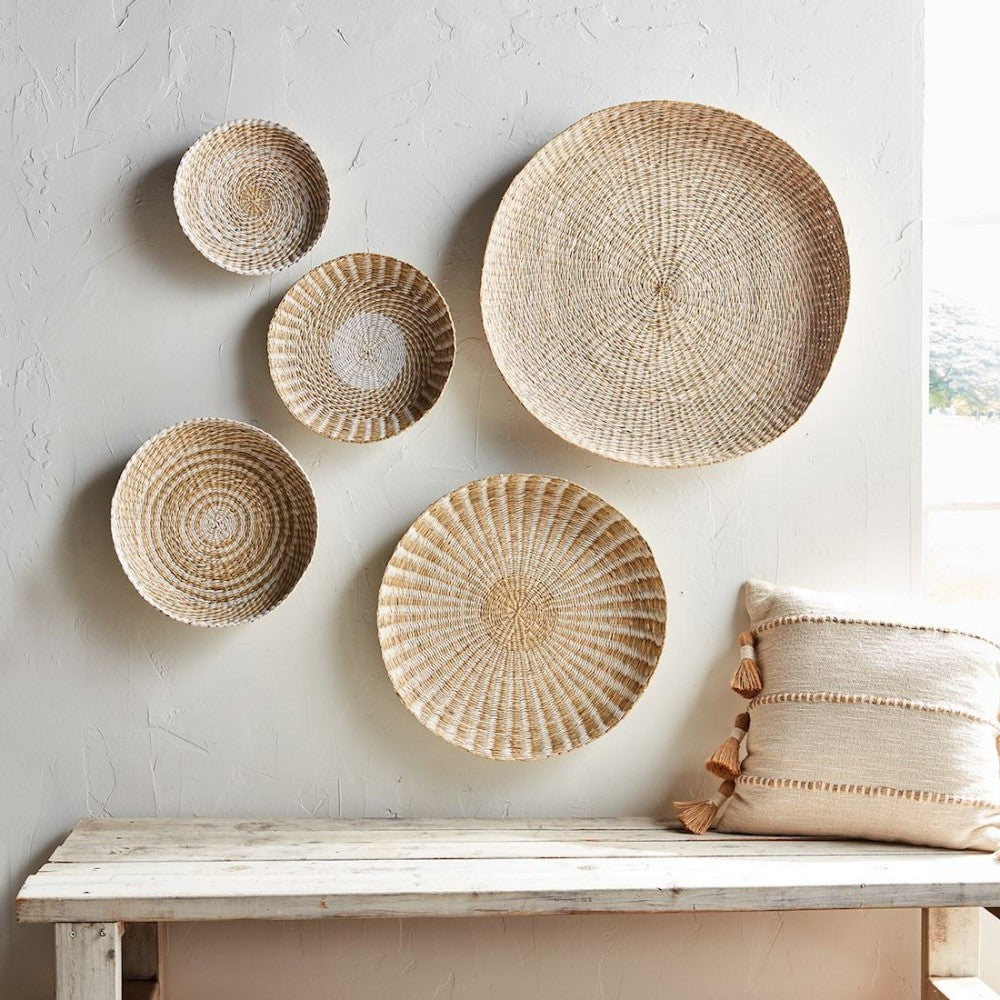 Woven baskets on wall above rustic bench with textured pillow.