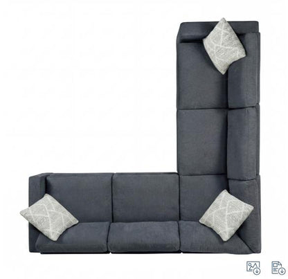 L-shaped charcoal sofa with three white patterned cushions.