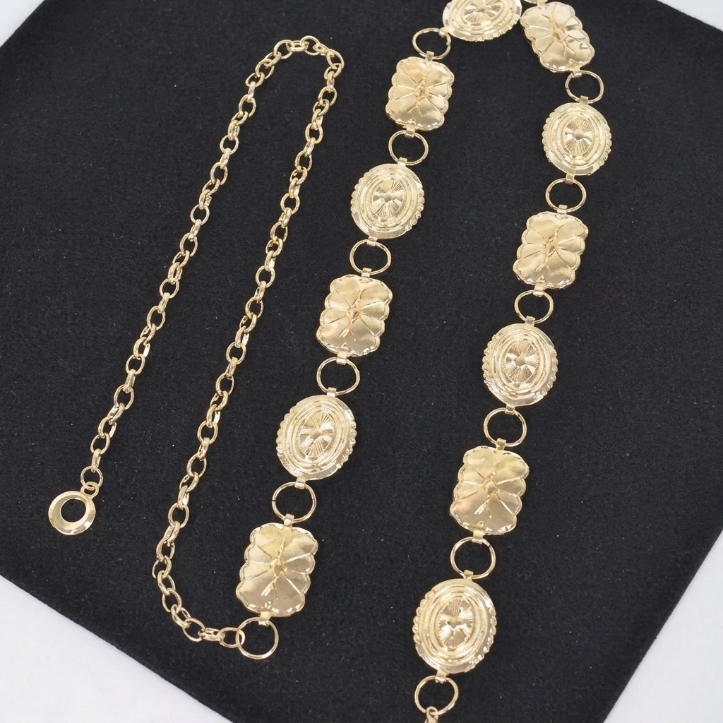Gold chain and ornate necklace on black fabric background.
