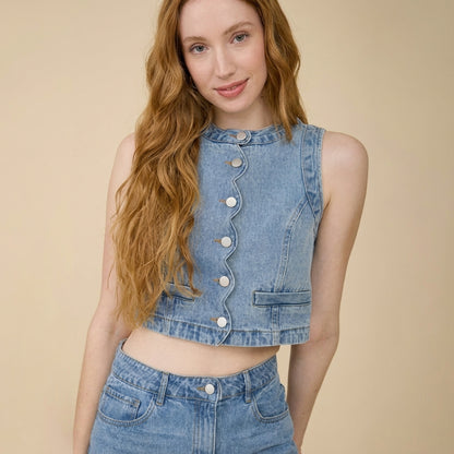 Woman with long hair in denim top and jeans, smiling at camera.