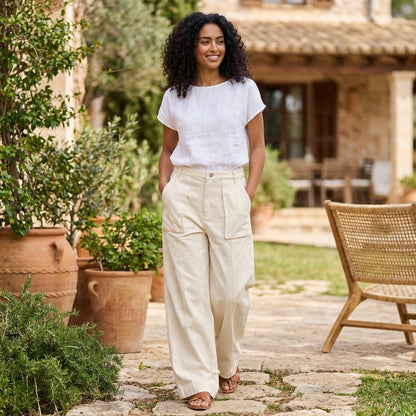 Woman in relaxed outfit walking outdoors by rustic house.