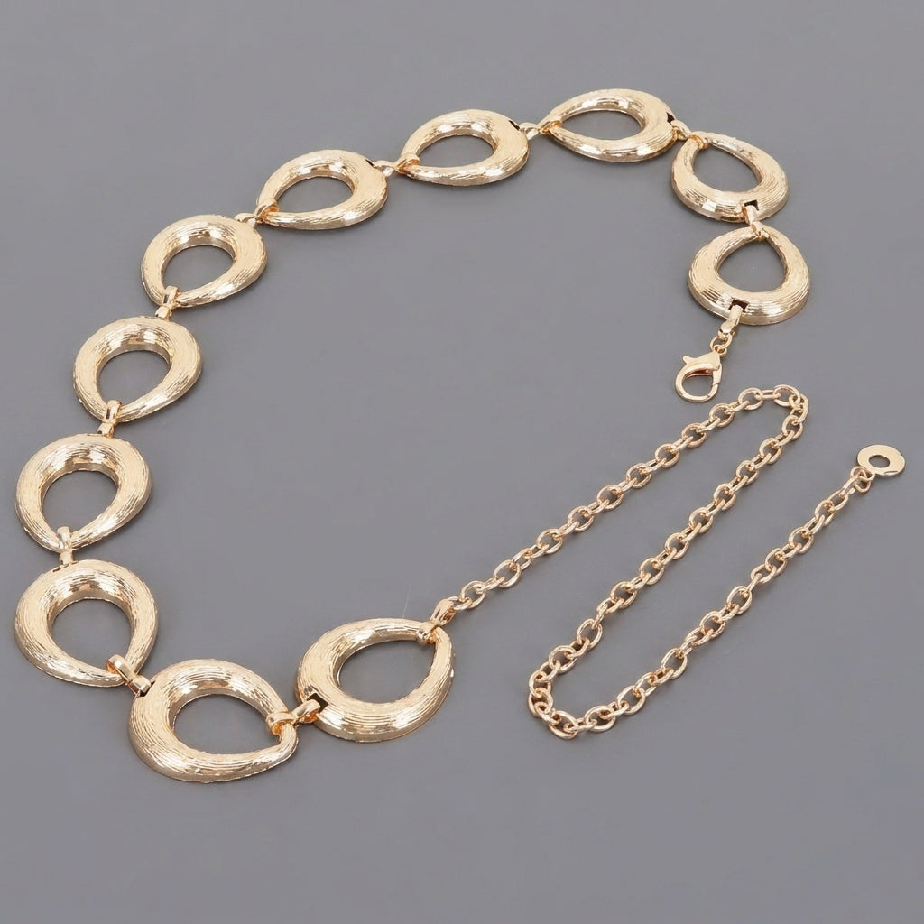 Gold textured link necklace with a chain extension on a gray background.