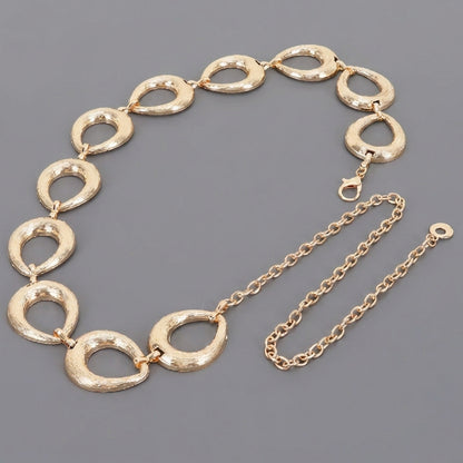 Gold textured link necklace with a chain extension on a gray background.