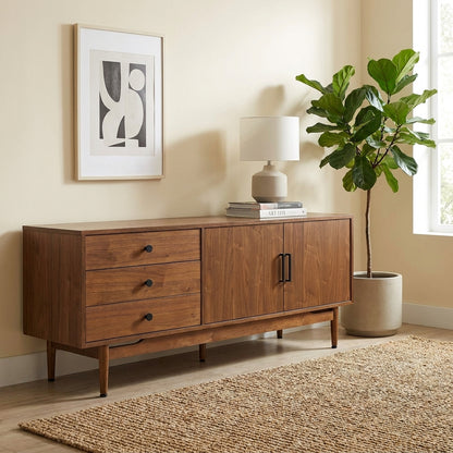 Mid-century sideboard with plant, abstract art, and lamp on a woven rug.