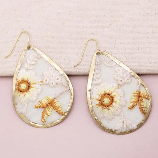 Teardrop earrings with floral embroidery and gold-tone borders.