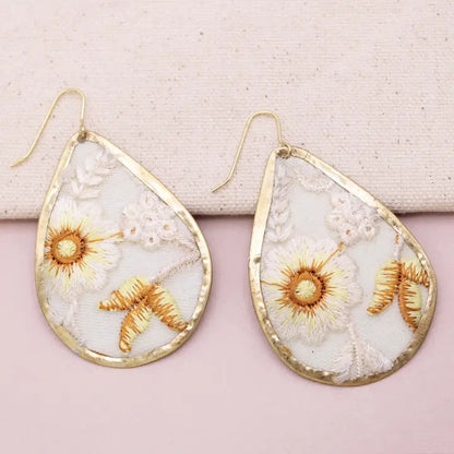Teardrop earrings with floral embroidery and gold-tone borders.