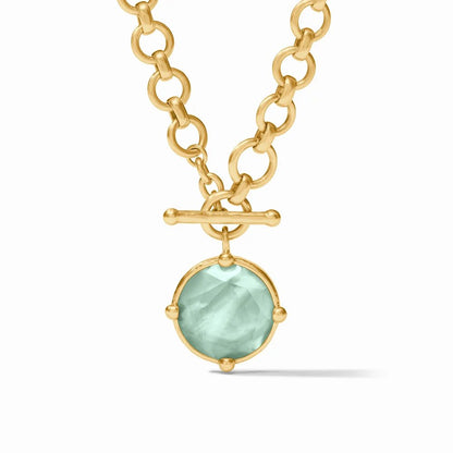 Gold chain necklace with a light blue gemstone pendant.