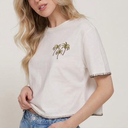 Woman in palm tree embroidered T-shirt and jeans.