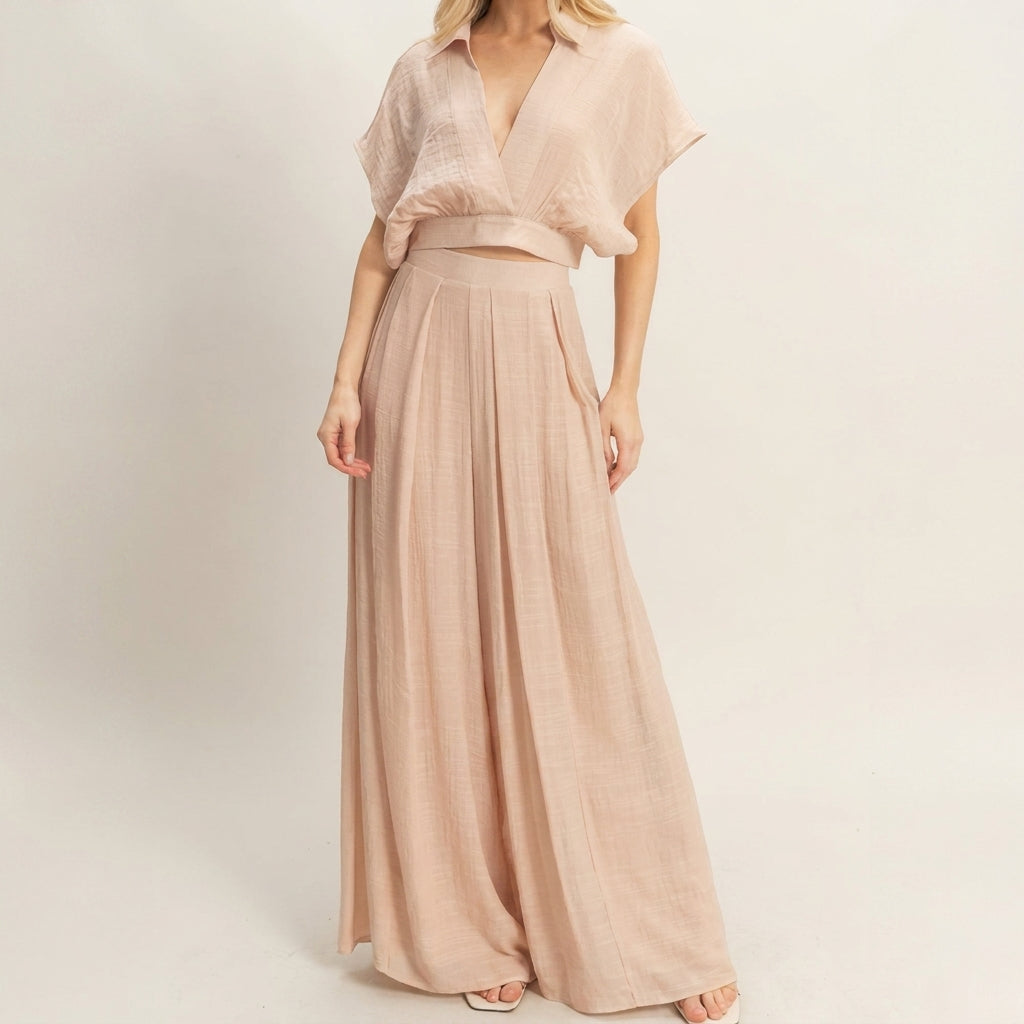 Woman in a beige flowy maxi dress, minimalist background.