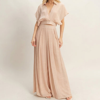 Woman in a beige flowy maxi dress, minimalist background.