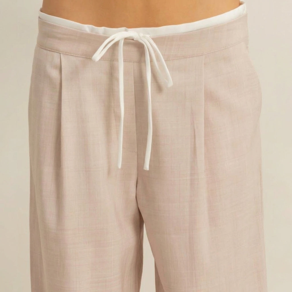 Beige pants with a white drawstring waist, close-up view.