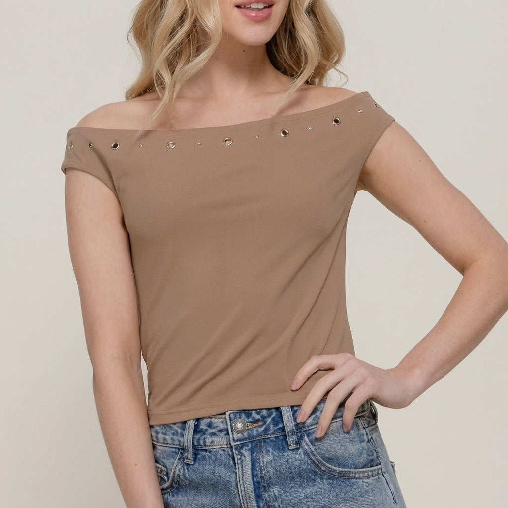 Woman in off-shoulder top with eyelets, blue denim jeans.