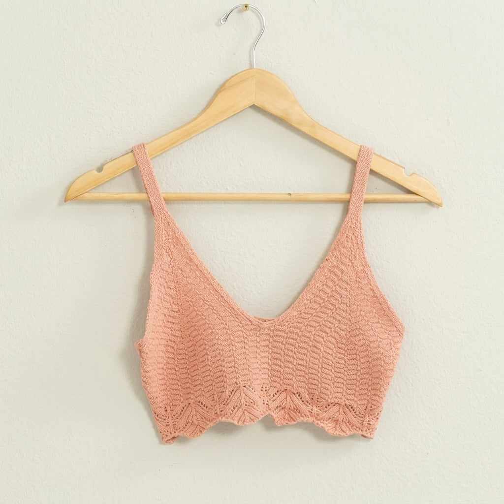 Pink knitted crop top on a hanger against a white background.