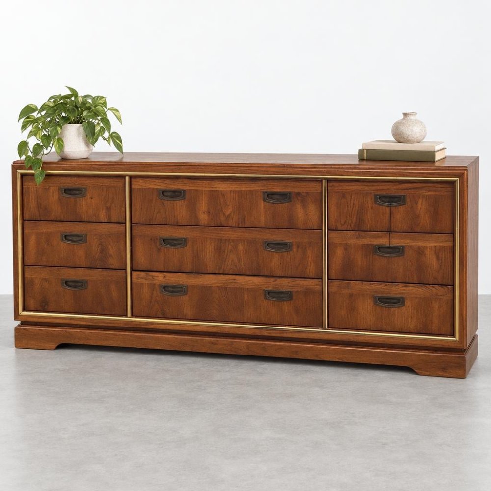 Wooden dresser with drawers, topped with a plant, books, and a vase.