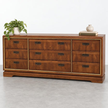 Wooden dresser with drawers, topped with a plant, books, and a vase.