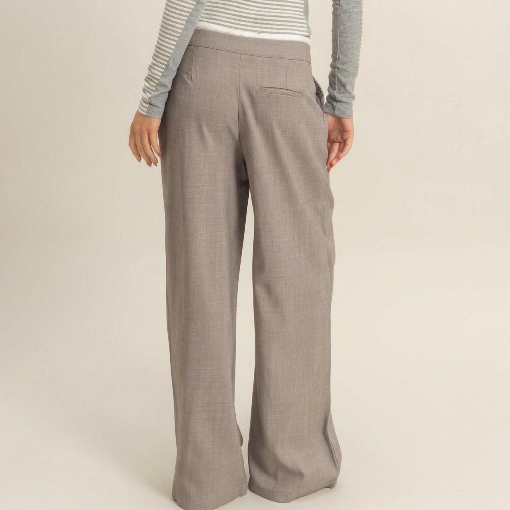 Person in gray wide-leg pants and a striped top, standing with back facing camera.