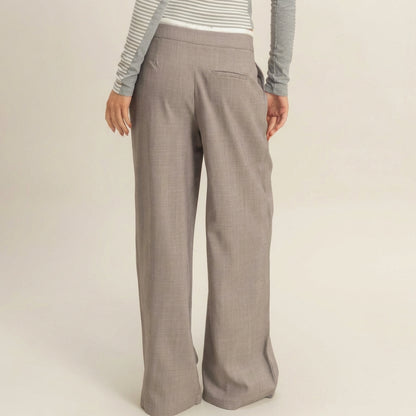 Person in gray wide-leg pants and a striped top, standing with back facing camera.