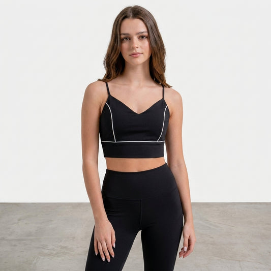 Woman in a black sports top and cap looking to the side.