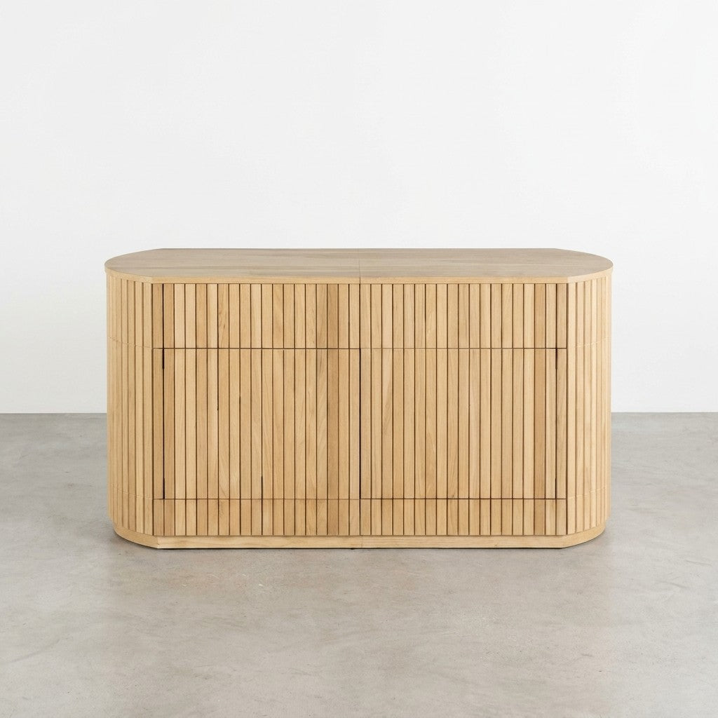 Oval wooden cabinet with vertical slats on a concrete floor.