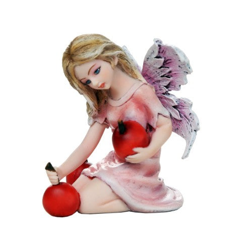 Fairy figurine with pink wings holding red apples.