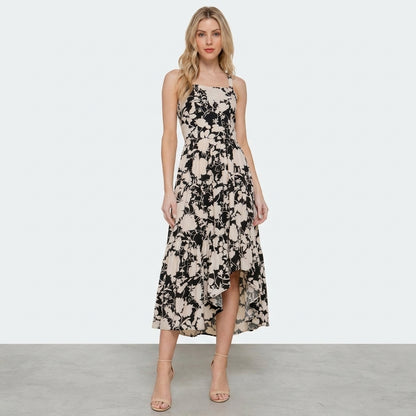 Woman in a floral dress and heels against a plain background.