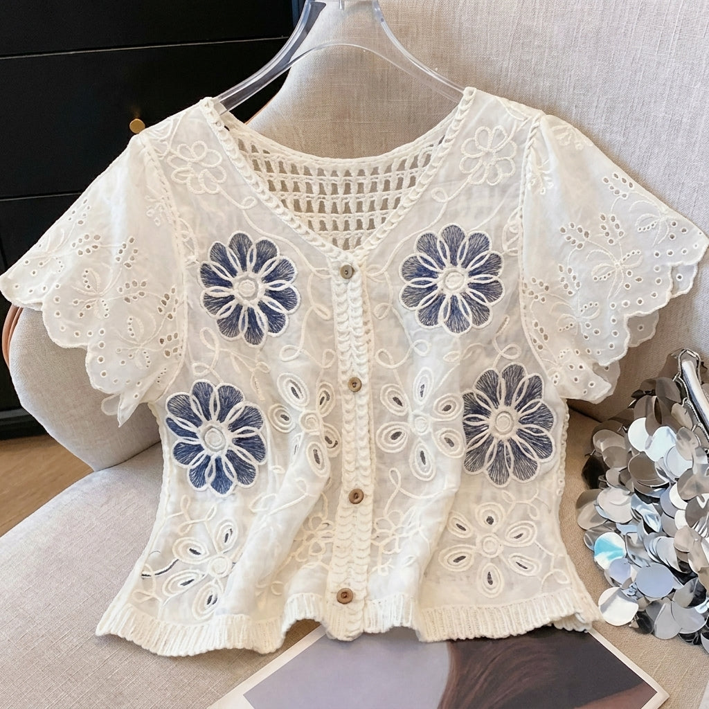 White lace top with blue floral embroidery and wooden buttons.