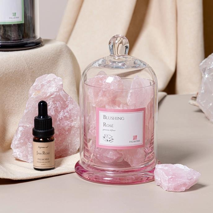 Pink crystals in a glass dome with a small dropper bottle.