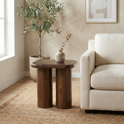 Modern living room with beige sofa, wood table, plant, and art.