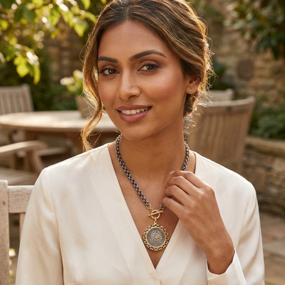 A smiling woman in a white top showcases a bold pendant necklace outdoors.