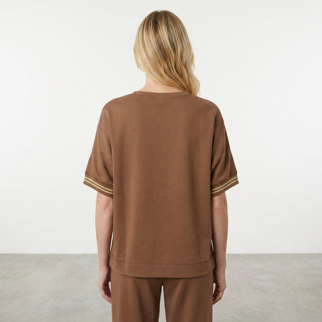 Person in a brown outfit, viewed from the back, in a minimal setting.