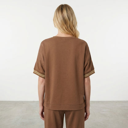 Person in a brown outfit, viewed from the back, in a minimal setting.