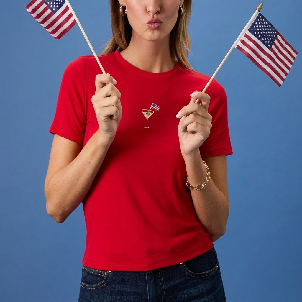 Woman in red tee holding two American flags against a blue background.