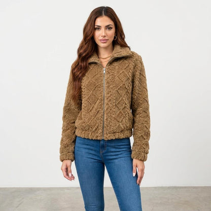 A woman models a brown textured zip-up jacket with blue jeans against a plain studio backdrop.