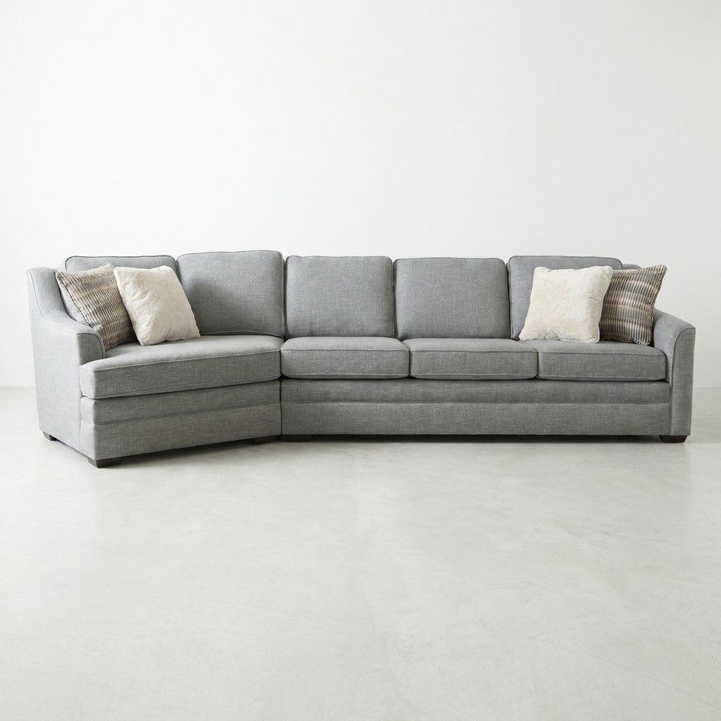 Gray sectional sofa with fluffy pillows on a white floor.